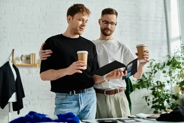 Two men, part of a stylish design duo, enjoy a coffee break together, holding cups and chatting. — Stock Photo