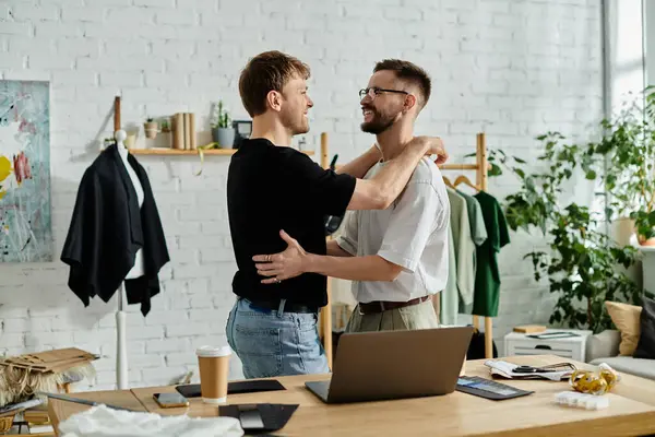 A gay couple collaborates on their laptop in a trendy designer workshop. — Stock Photo