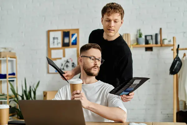Two men in his laptop, while working on designing trendy attire for his fashion workshop. — Stock Photo
