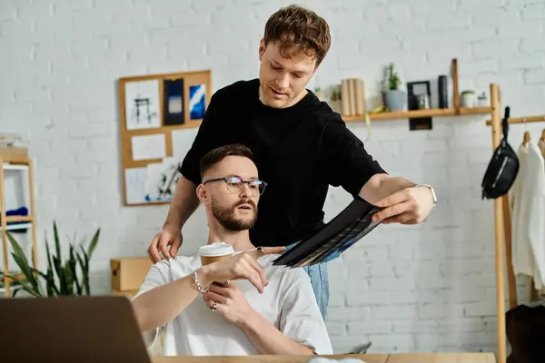 Gay couple working on designing trendy attire for his fashion workshop. — Stock Photo