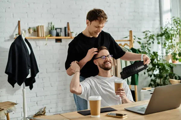 Man sitting at a laptop computer, designing trendy attire with his loved one. — Stock Photo