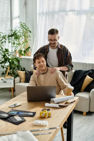 Men sits at a table, focused on his laptop as he collaborates on creating fashionable attire. — Stock Photo