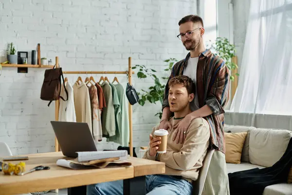 Un hombre bebe café en una mesa con su compañero, discutiendo sus últimos diseños. - foto de stock