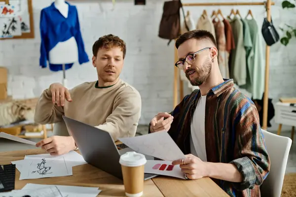 Dos hombres trabajando en un portátil en una mesa en un taller de diseño. - foto de stock