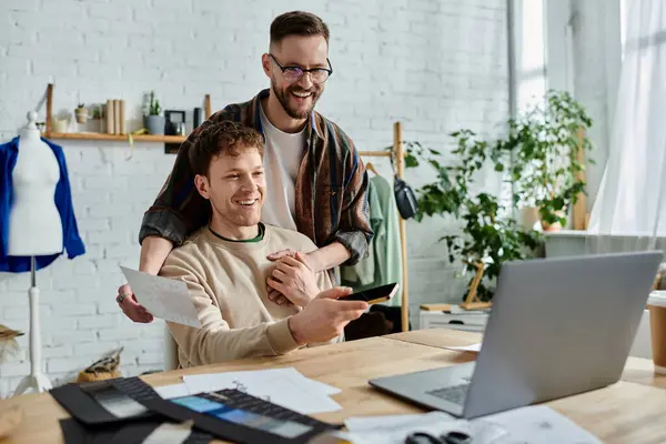 Men sits with a laptop, working passionately on trendy attire designs. — Stock Photo
