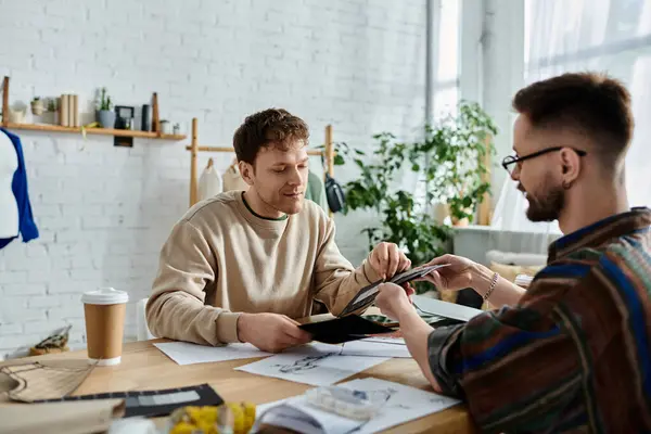 Two men working together on a trendy attire design in a designer workshop. — Stock Photo