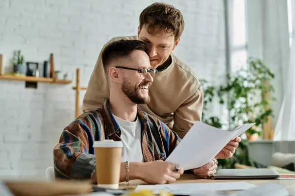 Deux hommes assis à table, examinant le papier, discutant des modèles de vêtements à la mode. — Photo de stock