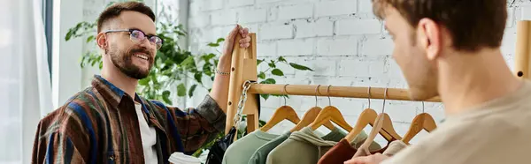 Dos hombres, una pareja gay, crean camisas elegantes en un taller de diseño. - foto de stock