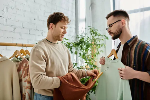 Two men in a designer workshop stand side by side, collaborating on creating trendy attire. — Stock Photo