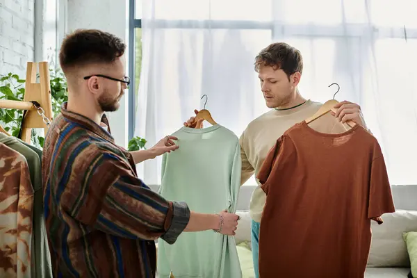 Two men, a gay couple, stand side by side in a designer workshop, working on creating trendy attire together. — Stock Photo