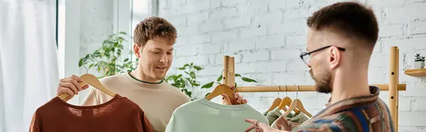 Gay couple examines a shirt hanging on a rack in a designer workshop. — Stock Photo