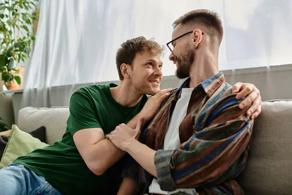 Gay couple creating trendy attire, sitting together on top of a couch in a designer workshop. — Stock Photo