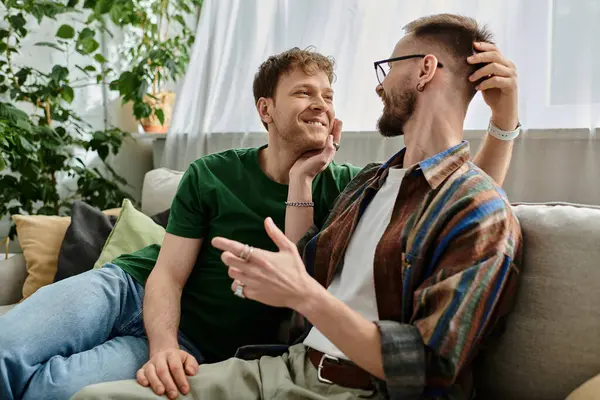 Двое мужчин, гей-пара, сидят на диване в дизайнерской мастерской, постоянно обсуждают и создают трикотажные наряды. — стоковое фото