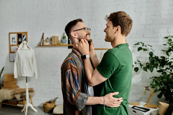 Two men stand together in a designer workshop, hugging and looking at each others eyes — Stock Photo