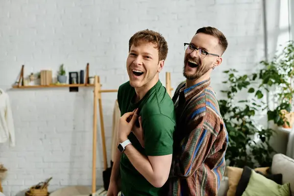 Two men, a gay couple, stand together and laughing in a designer workshop — Stock Photo
