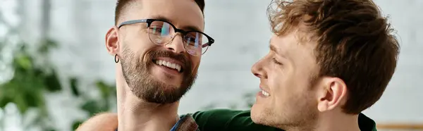 Dos hombres, una pareja gay, se mantienen unidos mientras trabajan juntos en un taller de diseño creando atuendos de moda. - foto de stock