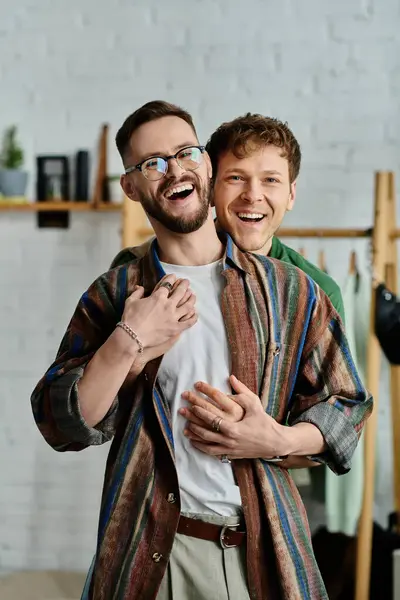 Два чоловіки, гомосексуальна пара, стоять пліч-о-пліч у дизайнерській майстерні, створюючи модний одяг разом. — стокове фото