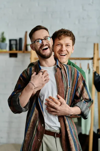 Two men, a gay couple, stand side by side in a designer workshop, creating trendy attire together. — Stock Photo