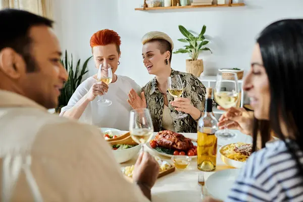 Diverse friends and a loving lesbian couple enjoy dinner together at home. — Stock Photo