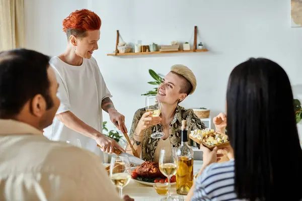 Eine vielfältige Gruppe von Menschen, darunter ein liebenswertes lesbisches Paar, genießt zu Hause ein gemeinsames Essen an einem Tisch. — Stockfoto