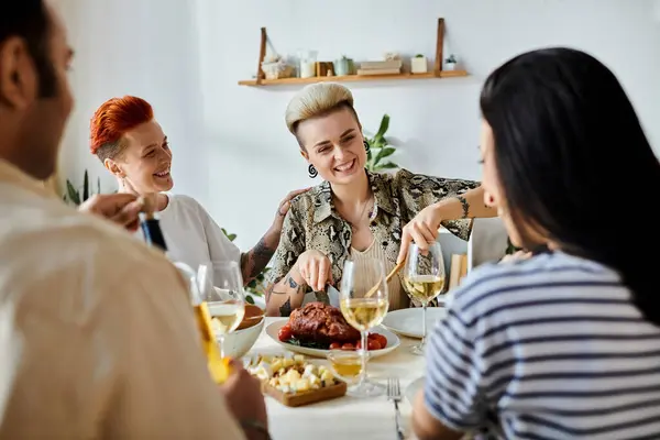 A diverse group of friends, including a loving lesbian couple, sit around a dinner table at home. — Stock Photo