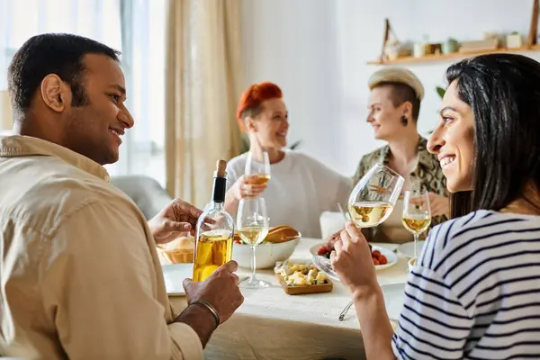 Diverse group of friends enjoying dinner and conversation around table with wine glasses. — Stock Photo