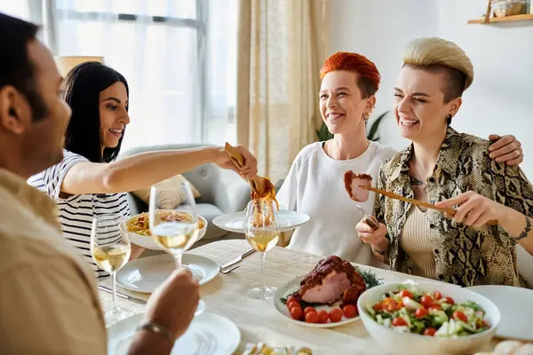 Eine Gruppe von Menschen beim gemeinsamen Essen, darunter ein liebevolles lesbisches Paar. — Stockfoto