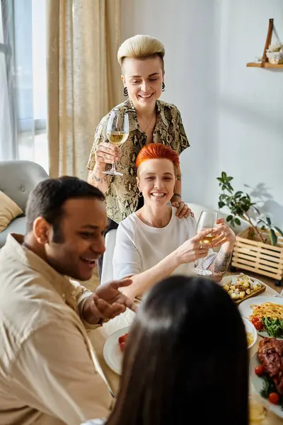 Diverse group enjoys dinner with loving lesbian couple at home. — Stock Photo