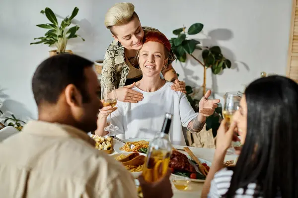Diverse group of friends joined by a loving lesbian couple enjoying dinner together. — Stock Photo