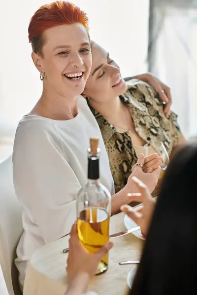 Две женщины наслаждаются бутылкой вина за столом, с друзьями. — стоковое фото