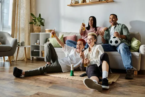Diverso grupo de amigos y una pareja lesbiana amorosa sentados en la parte superior de un sofá, compartiendo alegría y risa. - foto de stock