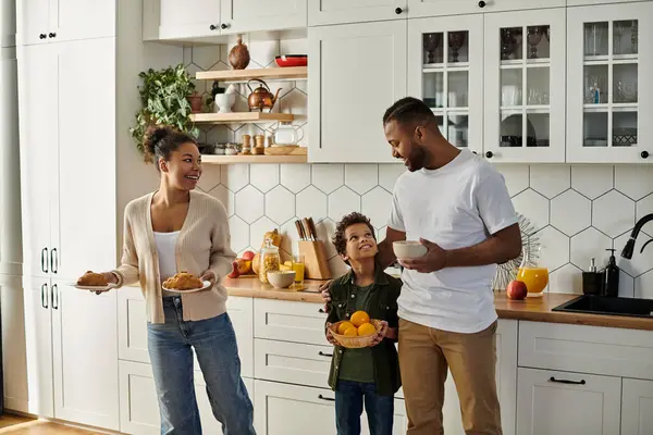 A man, woman, and child happily stand together in their kitchen. — Stock Photo