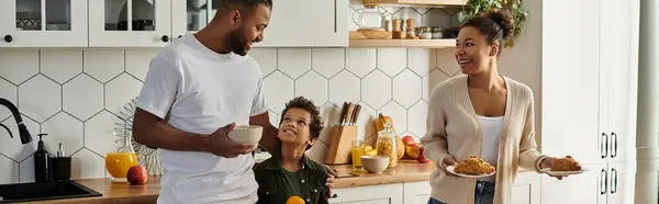 A man and a woman, a loving African American family with son, standing together in a kitchen. — Stock Photo