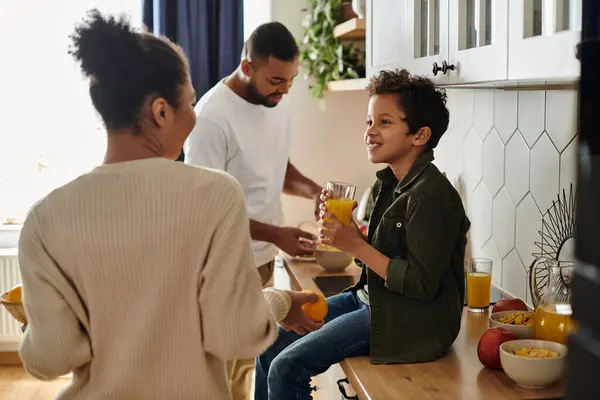 African American parents and son who sitting on kitchen counter, smiling happily. — Stock Photo