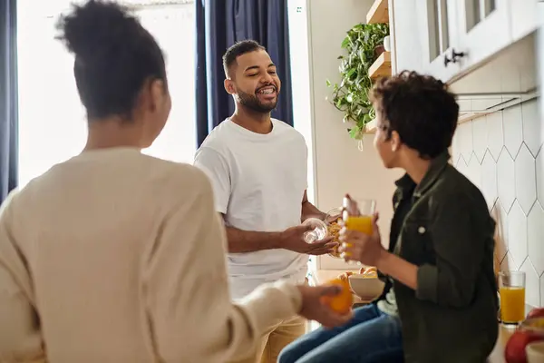 African American family stand around a kitchen, laughing and enjoying each others company. — Stock Photo