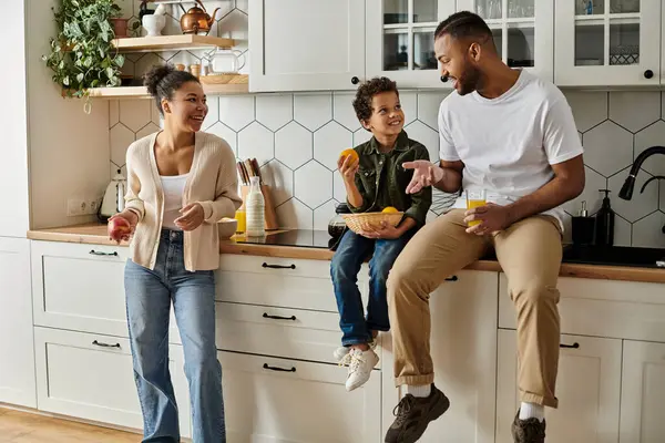 Afroamerikanische Familie lacht und plaudert am Küchentisch. — Stockfoto