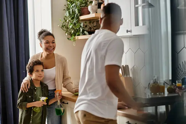 A man, woman, and young boy standing together in a home kitchen. — Stock Photo