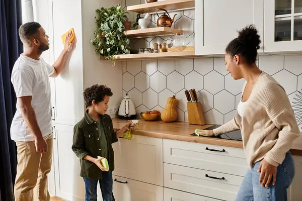 An African American man and woman are energetically cleaning the kitchen together, showing love and teamwork, with son. — Stock Photo