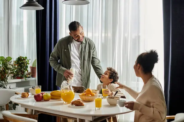 A man standing over a table overflowing with delicious food, wife and son. — Stock Photo