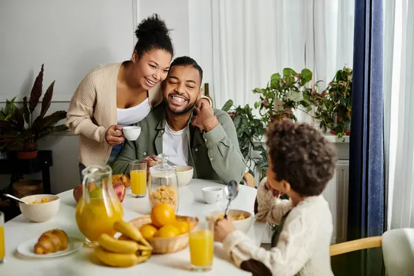 Un uomo e una donna afroamericani siedono con un bambino a un tavolo, mostrando amore e insieme. — Foto stock