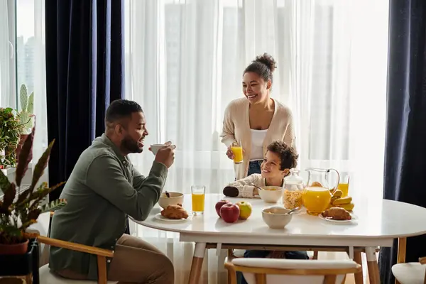 Famille afro-américaine partage le petit déjeuner à une table, profiter de l'autre compagnie. — Photo de stock