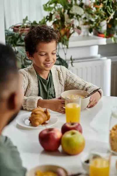 An African American man and boy sit at a table, enjoying breakfast together. — Stock Photo