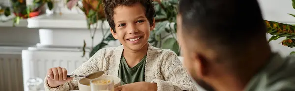 Young boy sitting at table, holding spoon. — Stock Photo