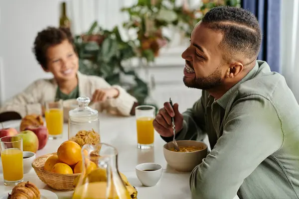 Uomini a tavola che mangiano cibo accanto a suo figlio. — Foto stock