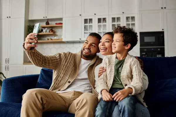 African American man takes selfie with his wife and child on couch. — Stock Photo