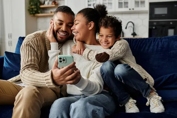 A man and woman in a loving embrace, taking a selfie with a cell phone, with son. — Stock Photo