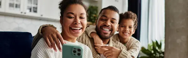 Man and woman smiling, taking selfie with cell phone, with son. — Stock Photo