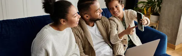 Three people, a loving African-American family, sit on a couch, engrossed in a laptop. — Stock Photo