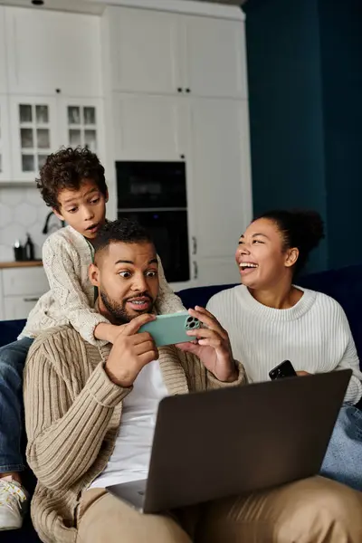 Man, woman, and child enjoy laptop together on couch. — Stock Photo