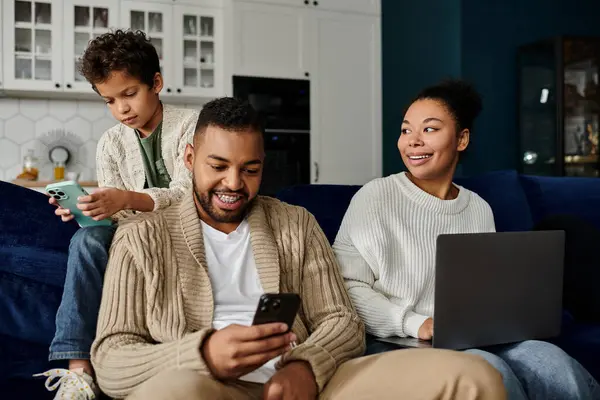 African american family engaged with a cellphone while sitting on a couch. — Stock Photo